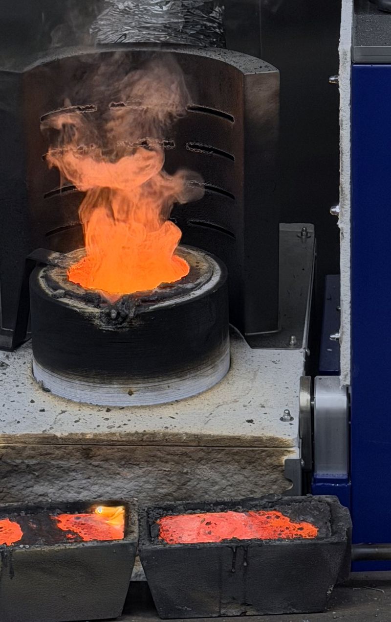 De inductieoven in de smelterij van BGP Edelmetaal met de smeltkroes op temperatuur en de afzuiging erboven